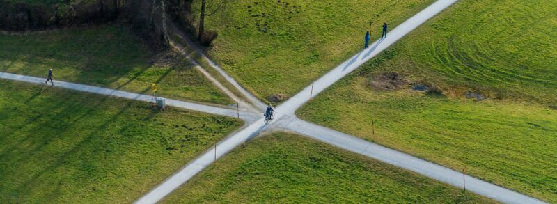 Aerial view of intersecting pathways across green fields, symbolising a mid-year pause, reflection and choosing the way forward.